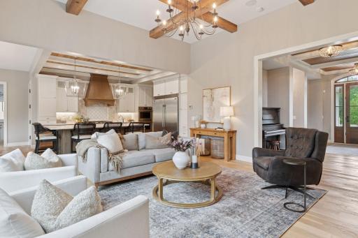 Beautiful open-concept living space with beamed ceilings and seamless flow from the living room to the kitchen and entryway.