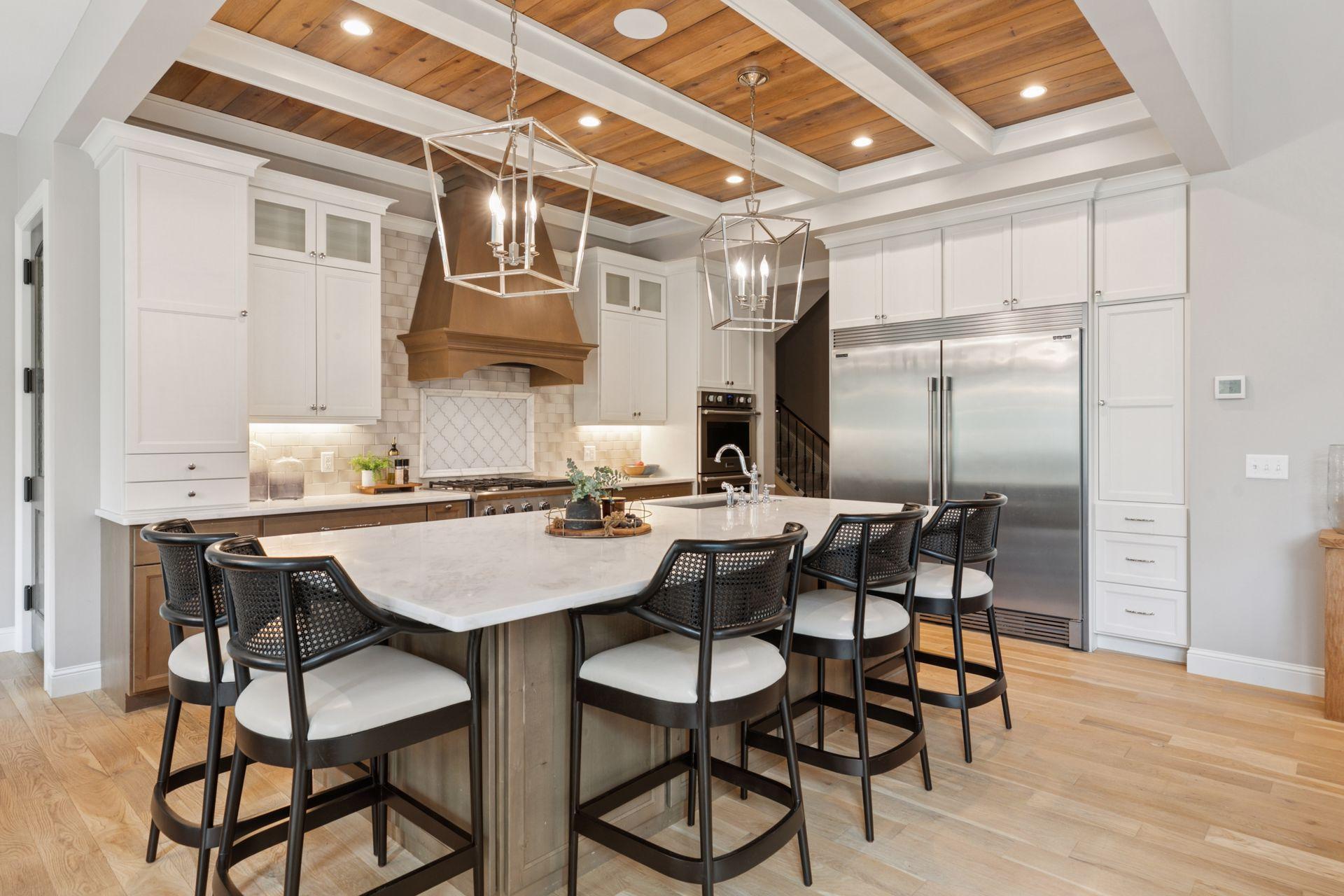 Stunning kitchen showcasing a large marble-topped island with seating, paneled ceiling with wood inlay, and high-end stainless appliances.