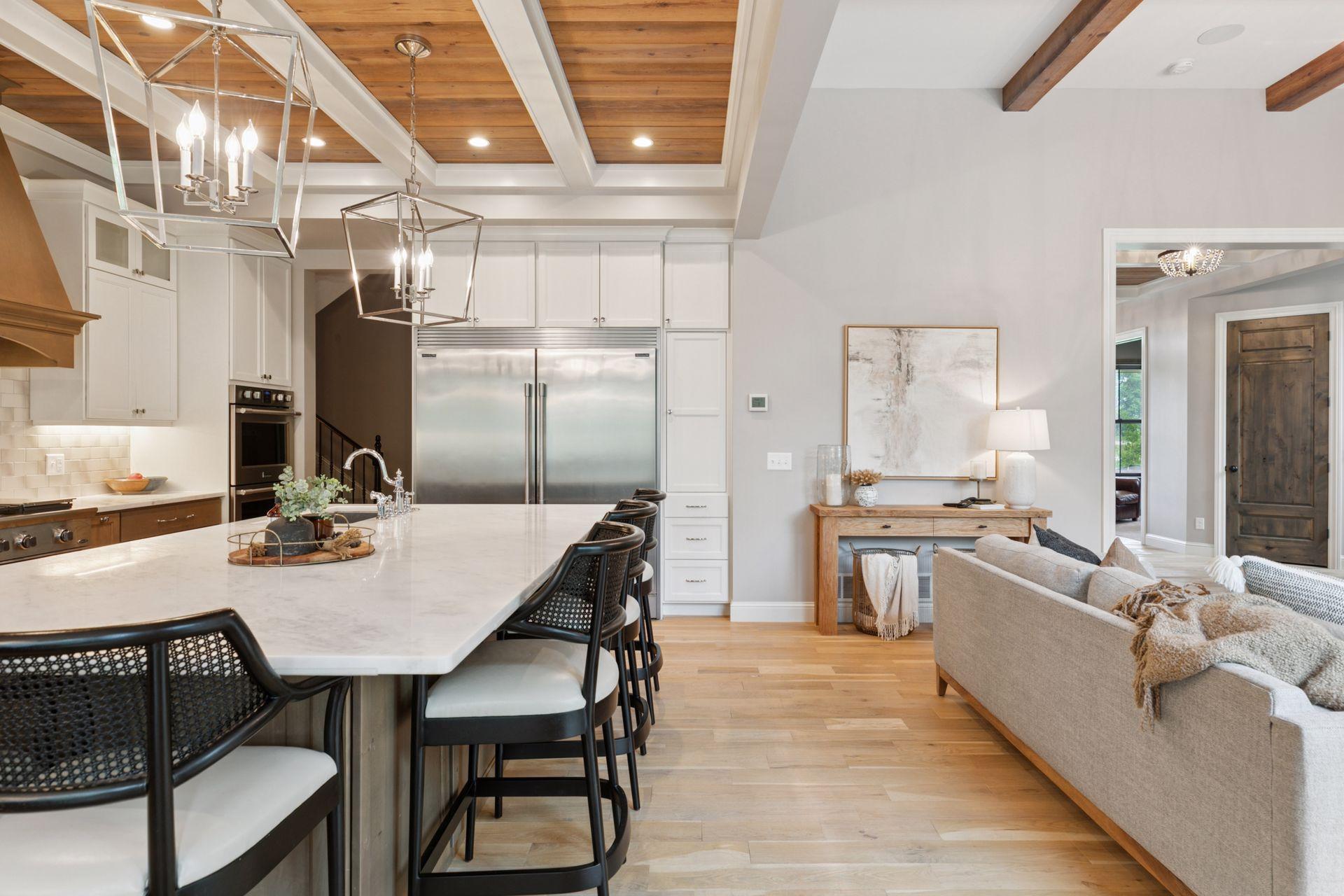 View from island highlights coffered ceilings with tongue-and-groove wood, stylish pendant lighting, and seamless flow into the great room.