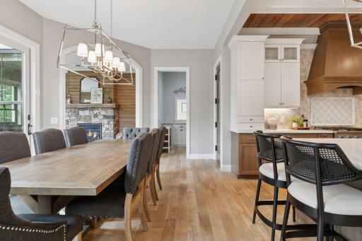 Elegant dining room with seating for ten, positioned to enjoy both backyard views and cozy ambiance from the adjacent stone fireplace.
