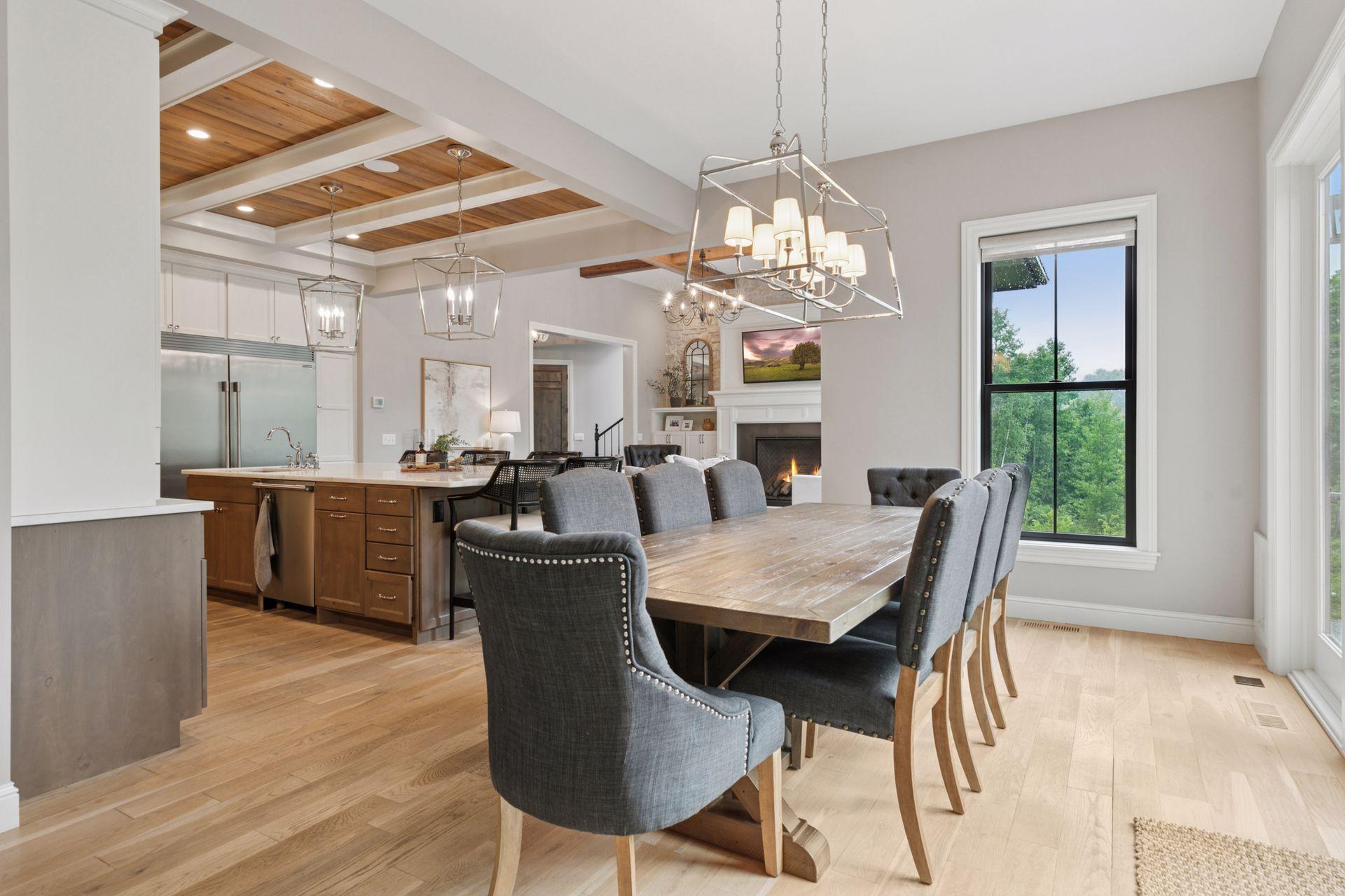 Open-concept dining area seamlessly connected to the gourmet kitchen and great room. Features refined finishes, wide-plank wood floors, and stunning ceiling detail with exposed beams.