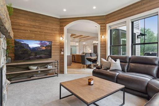 Sunroom provides an open connection to the kitchen and dining area through a graceful arched opening. Complete with wood paneling, large windows, and ambient sconcesâideal for relaxing or entertaining.