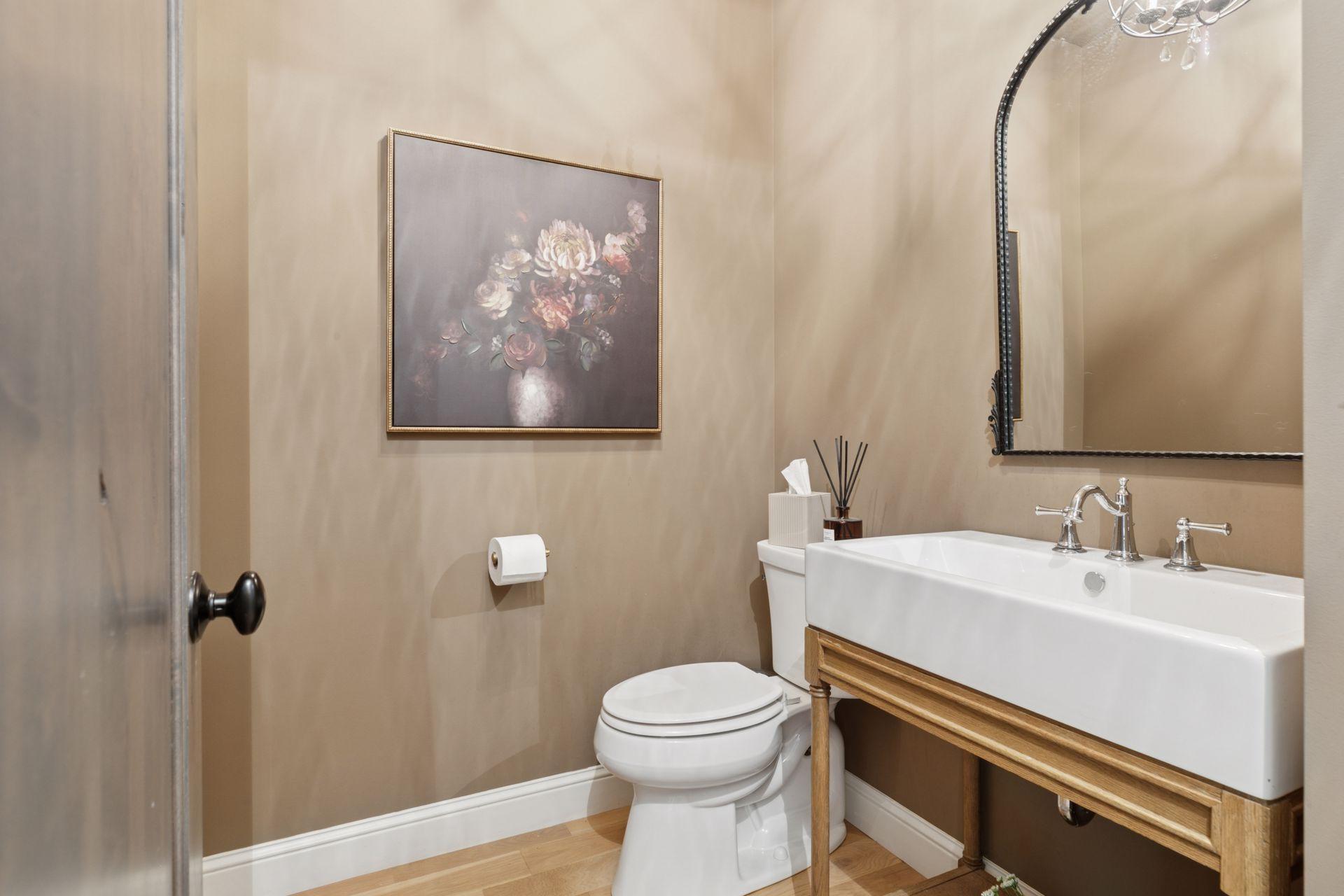 Elegant main-level powder room featuring a sleek rectangular vessel sink with chrome fixtures, warm taupe walls, and tasteful accent art creating a cozy, upscale ambiance.