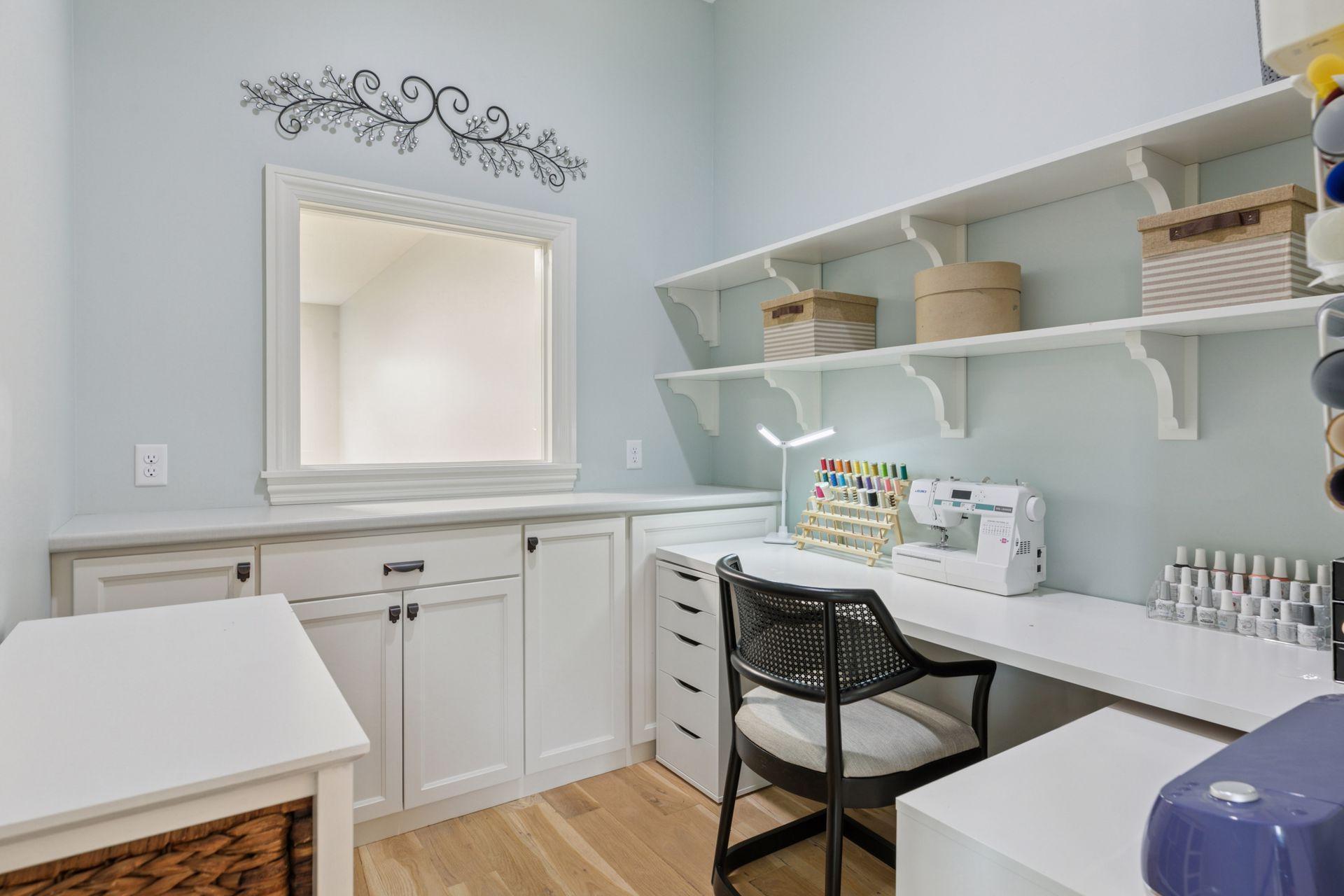 Dedicated craft or office space with custom built-ins, open shelving, and a long work surface ideal for sewing, organizing, or working from home. Clean design and excellent lighting for productivity. The window overlooks the indoor sport court.