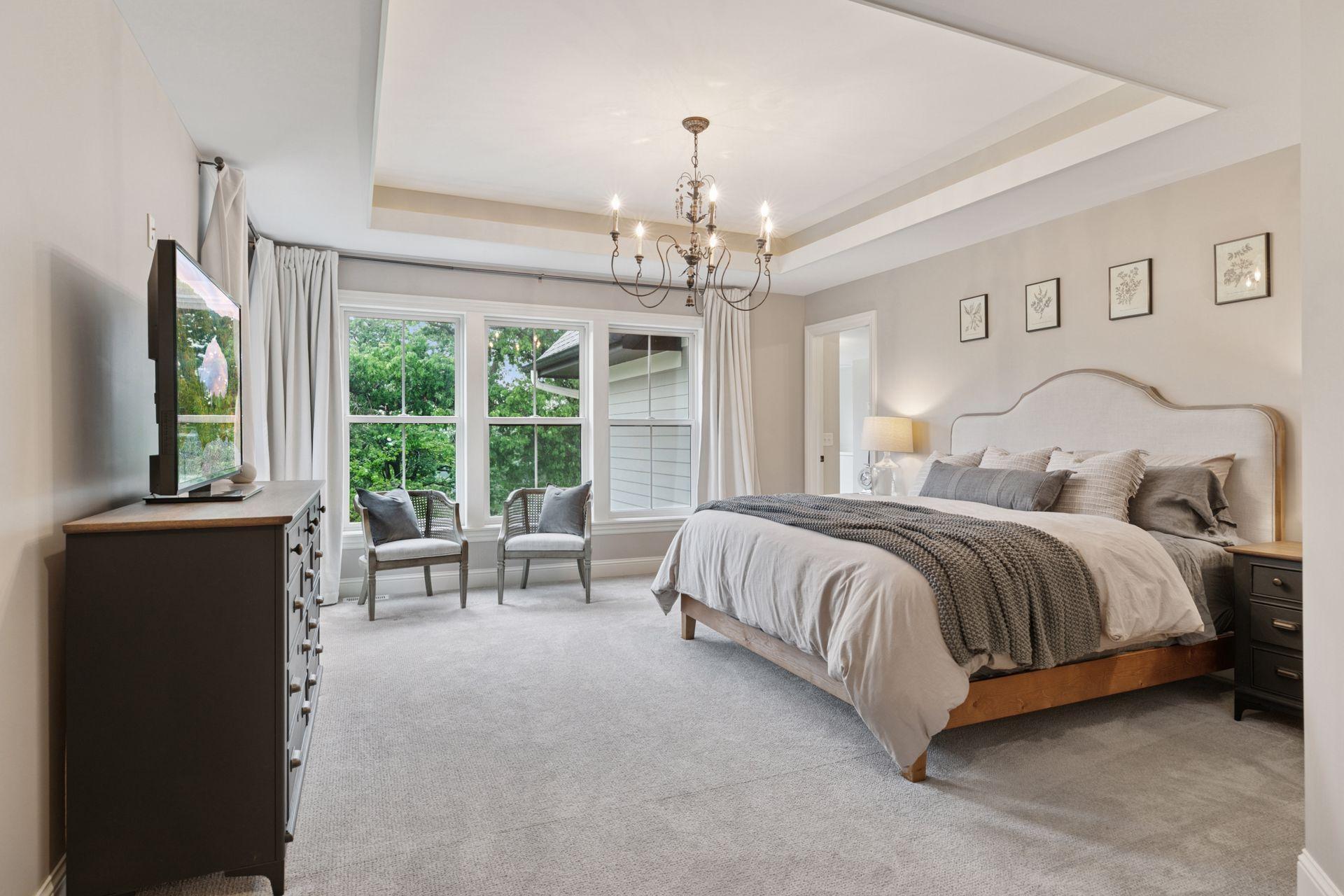 Retreat to a bright and airy owner’s suite featuring a tray ceiling, large picture windows, plush carpeting, and space for a cozy sitting area.