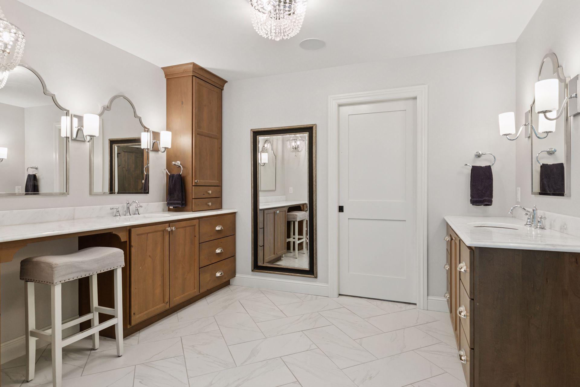 Dual vanities, custom cabinetry, a makeup counter, and sparkling chandeliers create a spa-like experience in this generous primary bathroom.