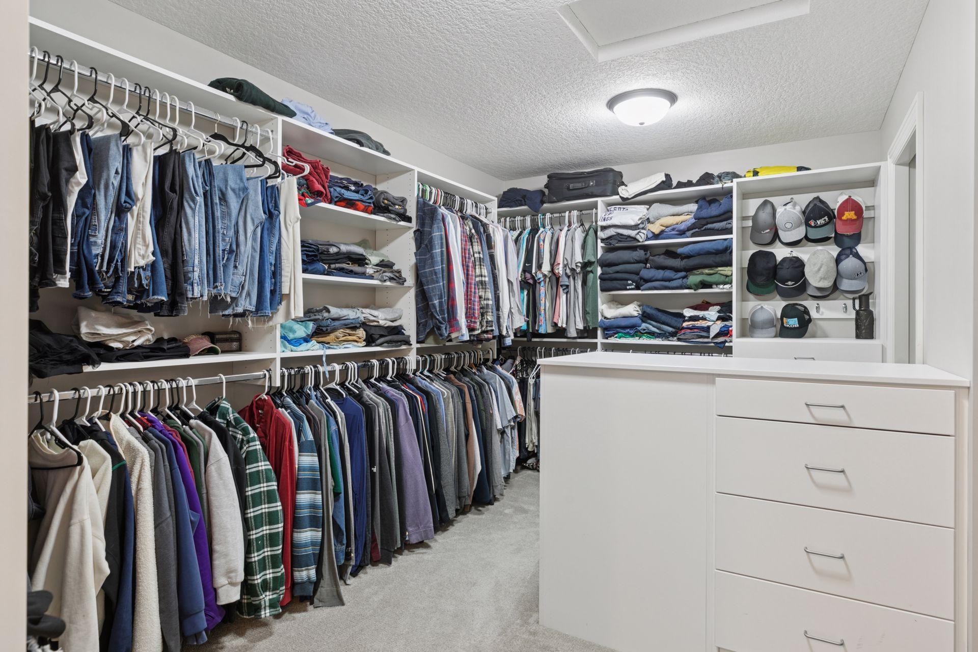 Walk-in closet with extensive built-in shelving, double hanging rods, drawer storage, and dedicated hat display.
