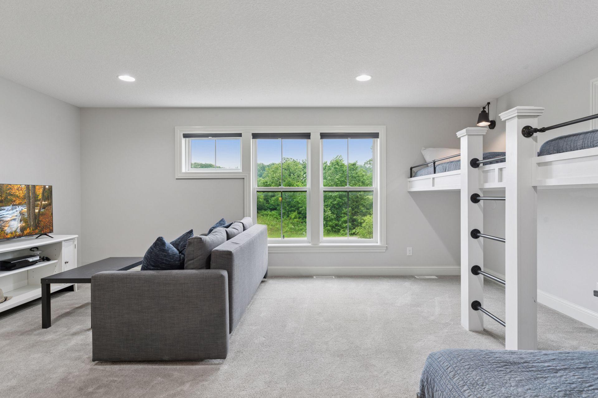 Bonus room view showcasing built-in bunk beds and a cozy TV sitting area with lush views through oversized windows.