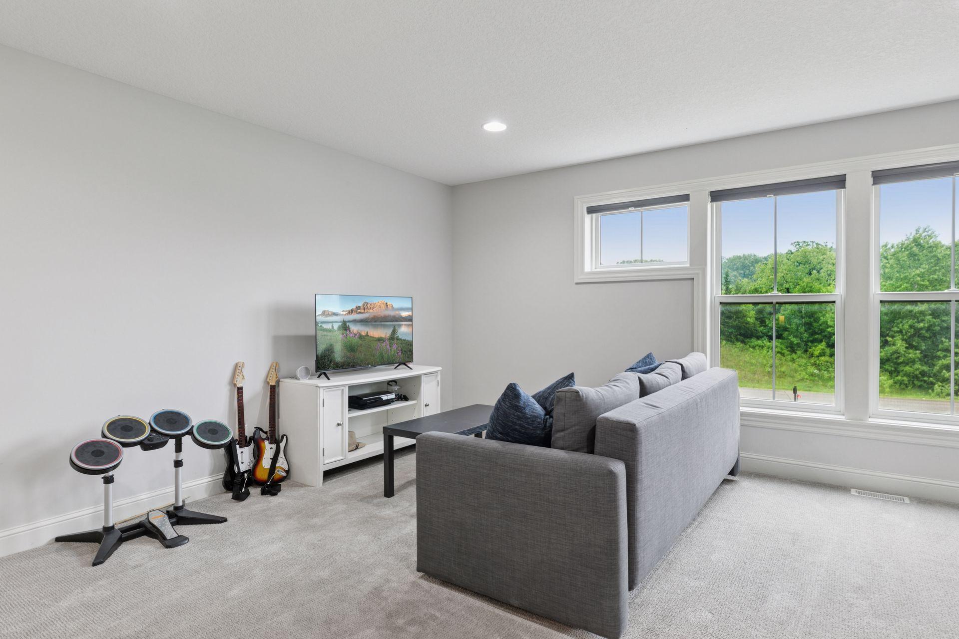 Upper-level bonus room with large windows, lush views, and space for entertainment and music.