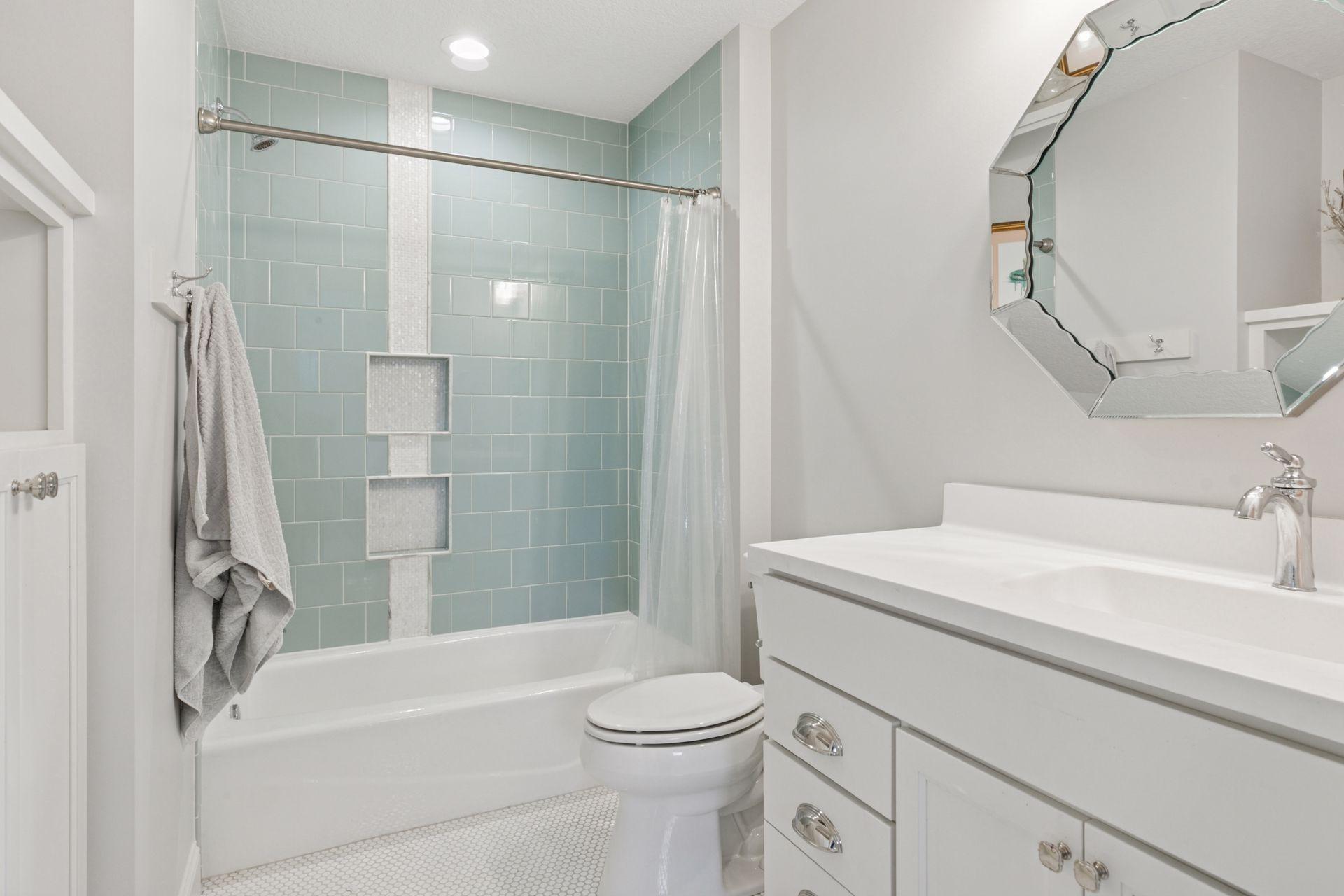 Bathroom with stylish seafoam green subway tile, built-in shower niches, and designer mirror.