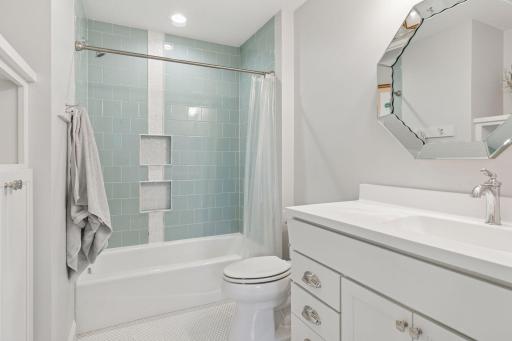 Bathroom with stylish seafoam green subway tile, built-in shower niches, and designer mirror.