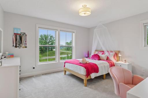 Charming bedroom with ensuite bath and walk-in closet featuring bright pink accents and tree-lined views.