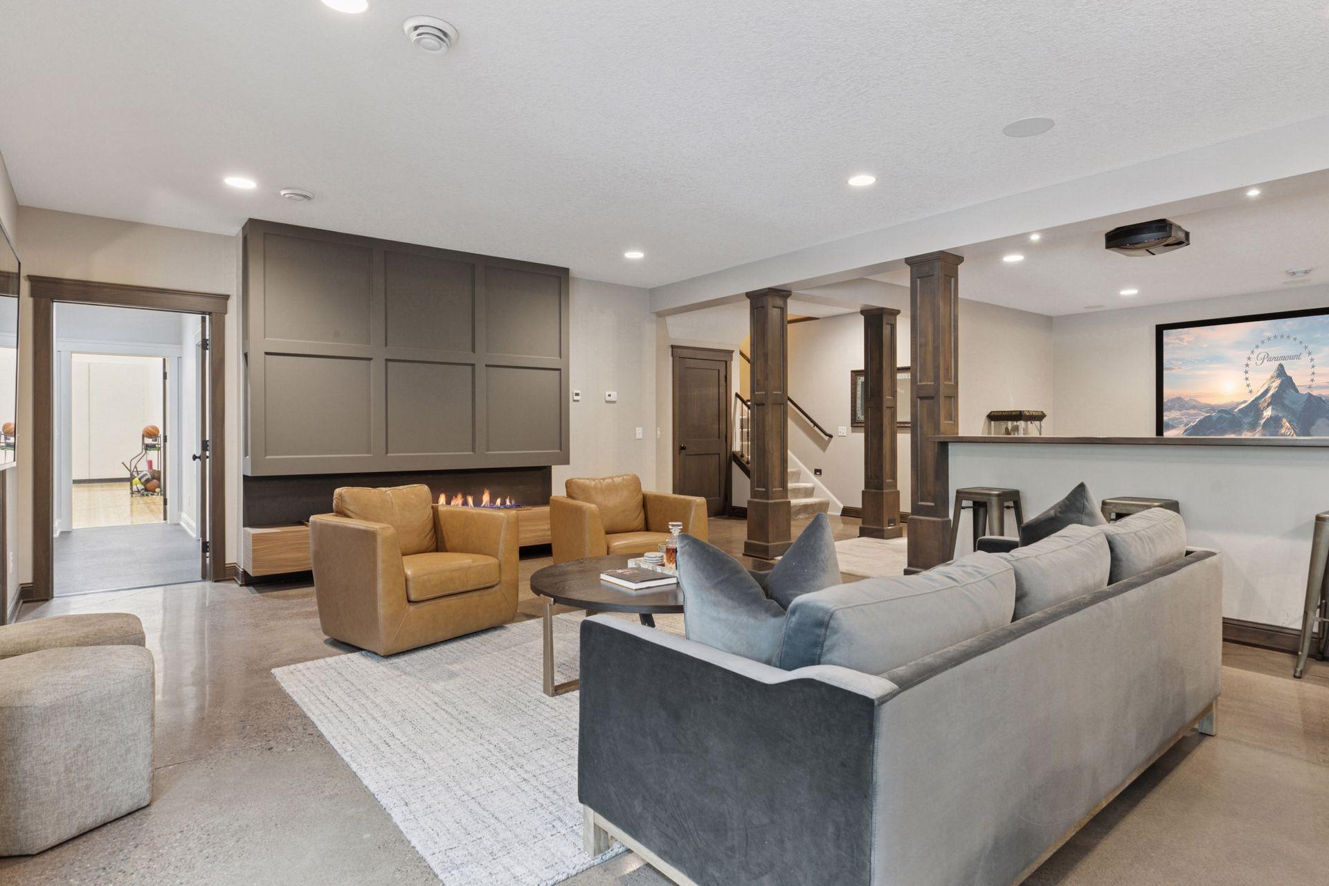 Warm and inviting lower-level lounge featuring a sleek fireplace, neutral tones, and polished concrete floors with in-floor radiant heat.