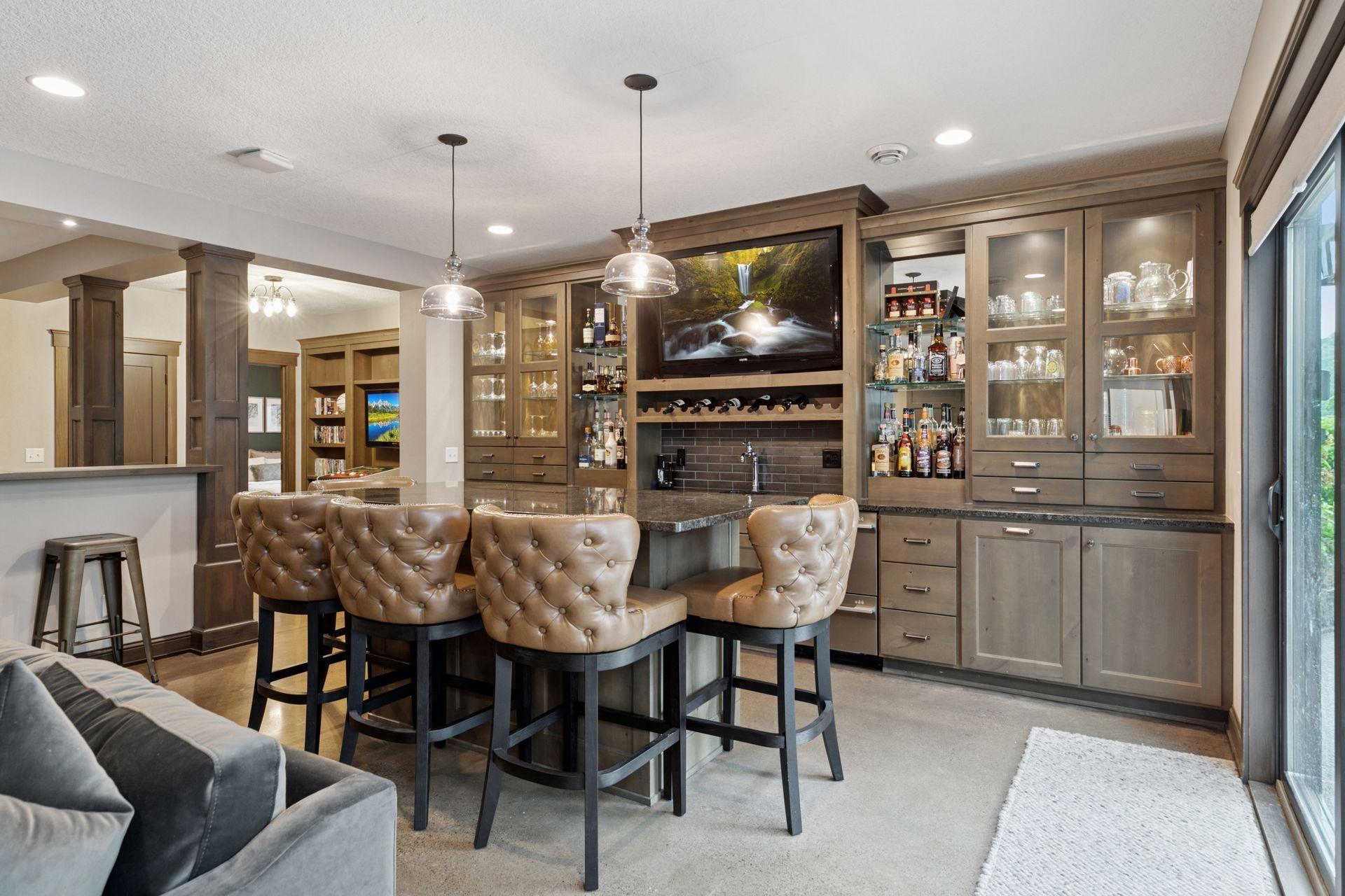 Open-concept bar and seating area with stool-lined counter, built-in display cabinetry, and pendant lighting above the bar.