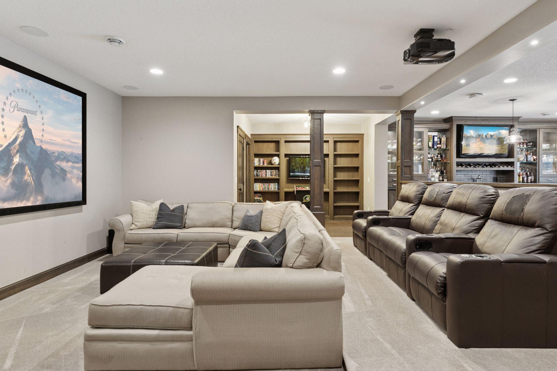 Comfortable home theater with a large screen, sectional seating, and soft carpet—perfect for relaxing and watching movies.
