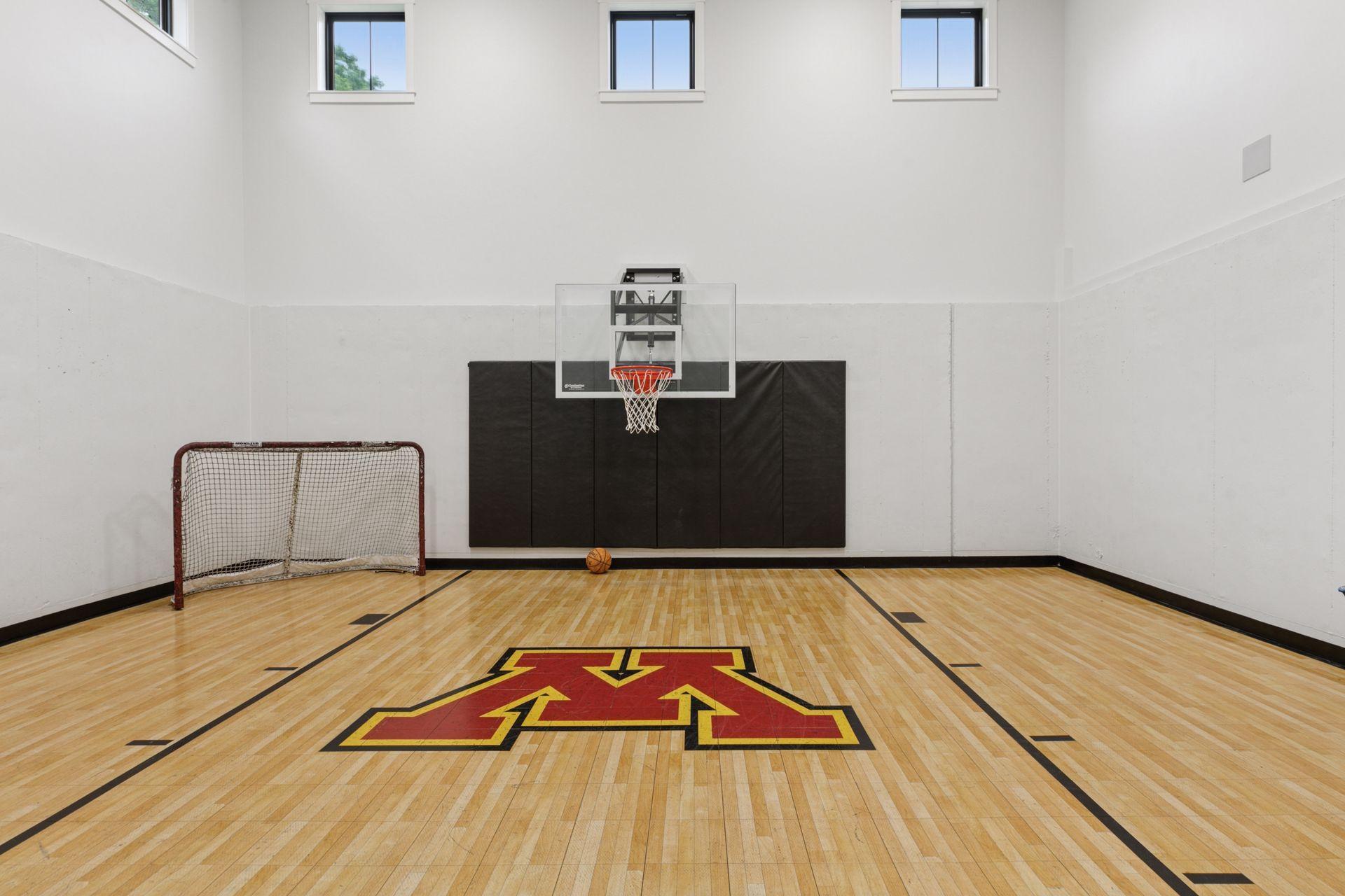 Impressive indoor sport court with full-height walls, basketball hoop, hockey goal, and custom floor design—ideal for active living and all-season play.