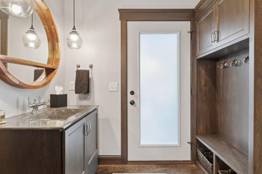 Stylish lower-level bath with modern lighting, dual-sink vanity, built-in cubbies, and direct pool accessâdesigned for convenience and functionality.