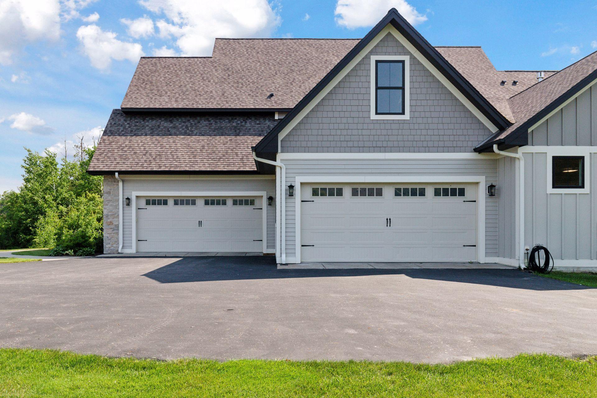 Expansive four-car radiant floor heated garage with carriage-style doors and ample space for vehicles, tools, and storage.