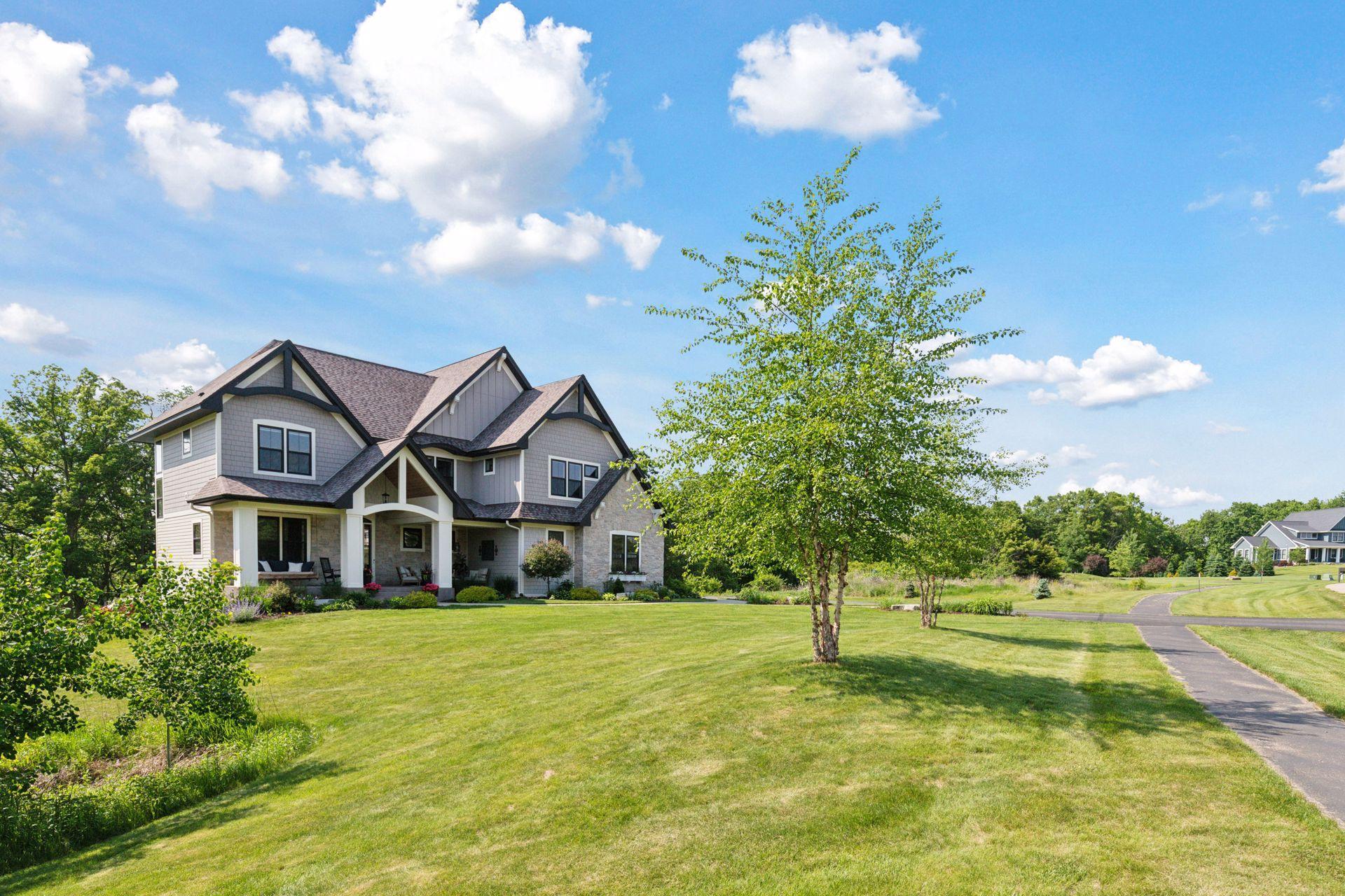 Beautiful side view of the home with sweeping lawn, tree-lined backdrop, and charming curb appeal in a tranquil setting.