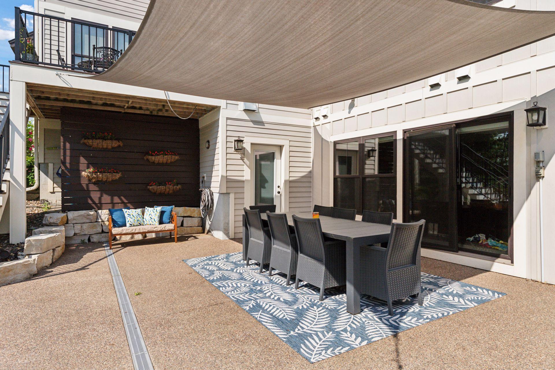 Stylish covered dining area sits beneath custom shade sails and beside oversized sliding glass doors—offering seamless transition from indoor meals to outdoor gatherings.