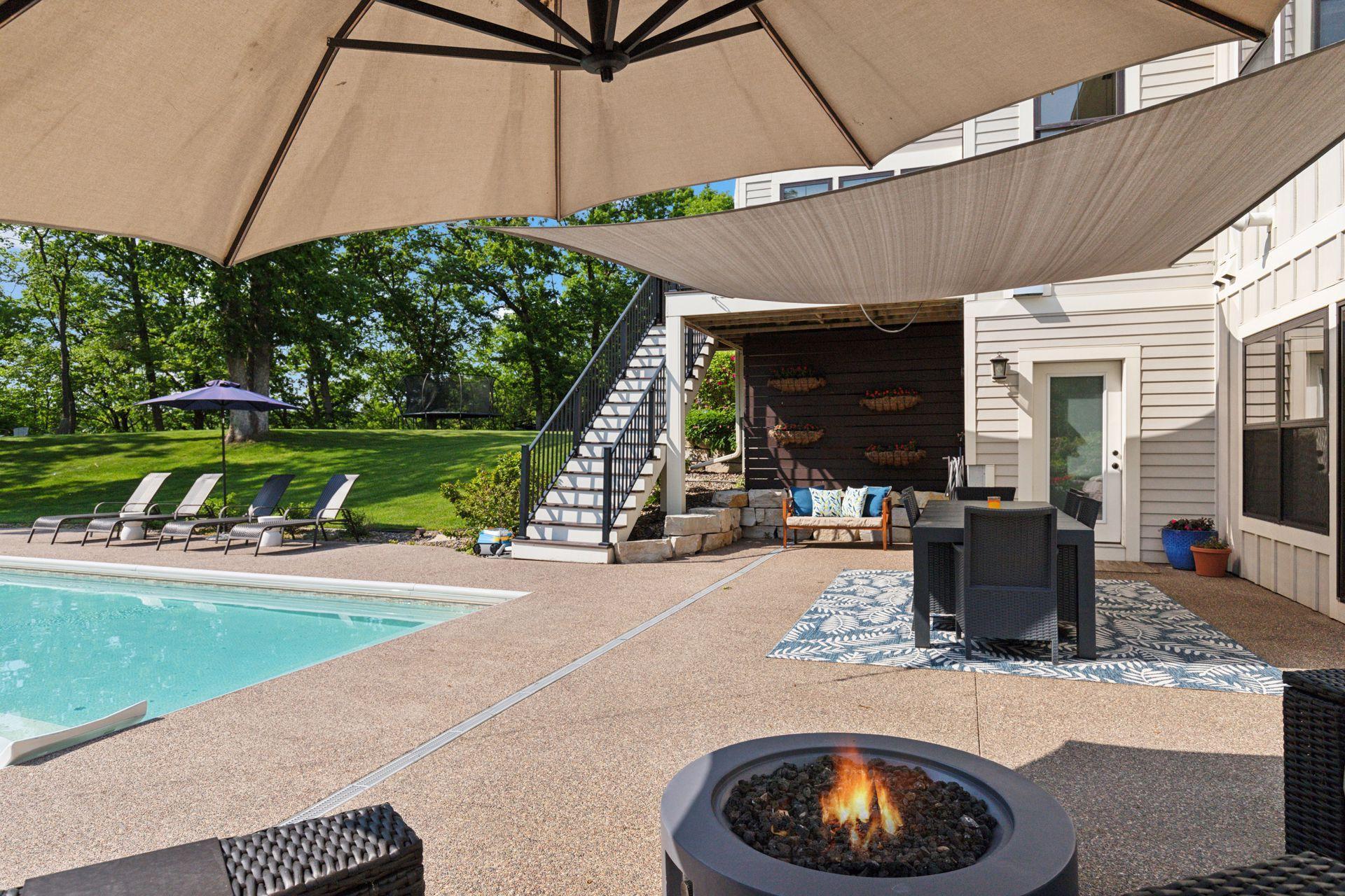 Covered entertaining space features an outdoor dining area, patio seating, and sunshade sails. Ideal for al fresco meals, summer parties, or shaded afternoon lounging.