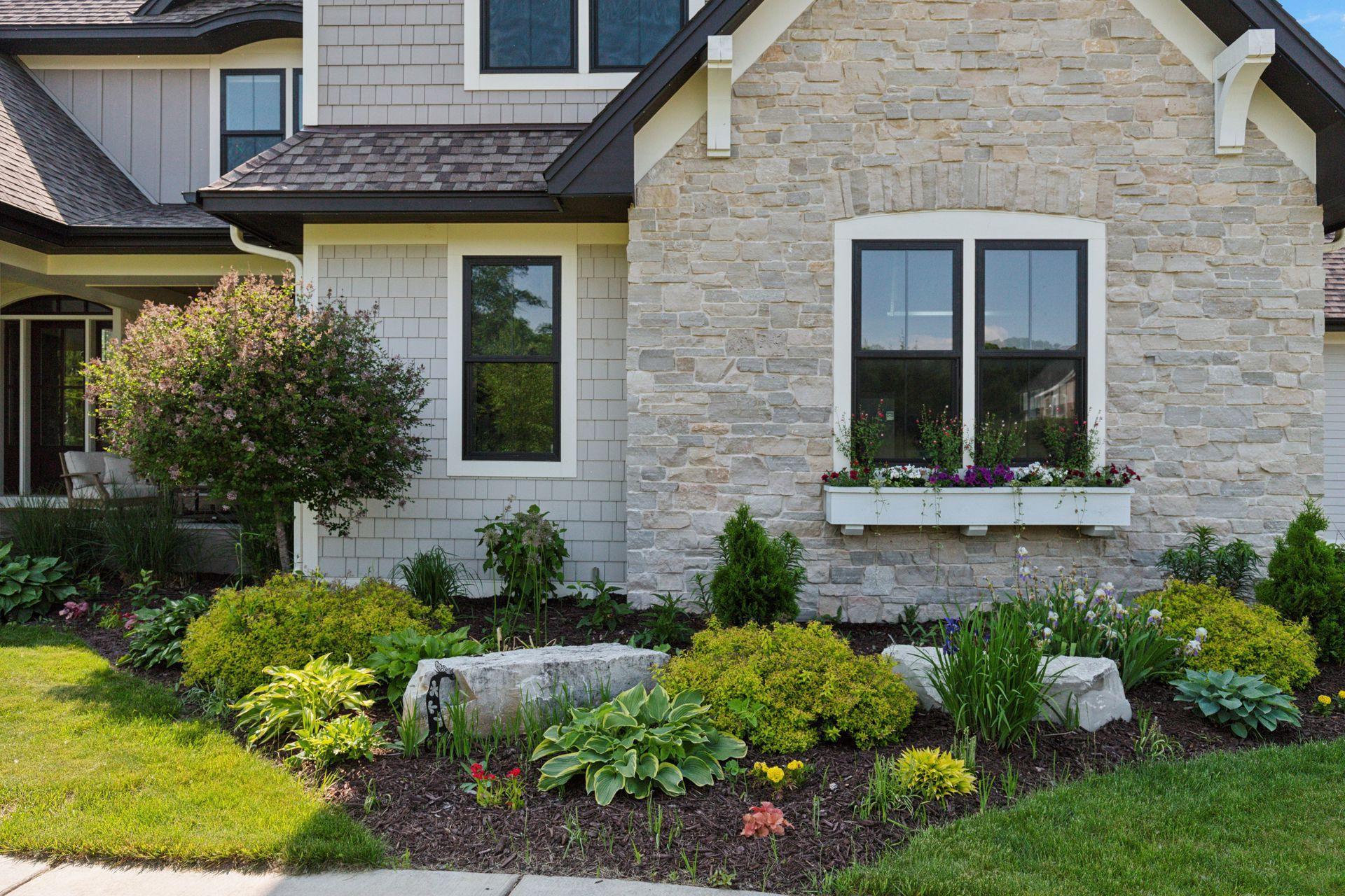 Close-up of stone facade and custom window box with blooming flowers—adds warmth and charm to the front elevation.