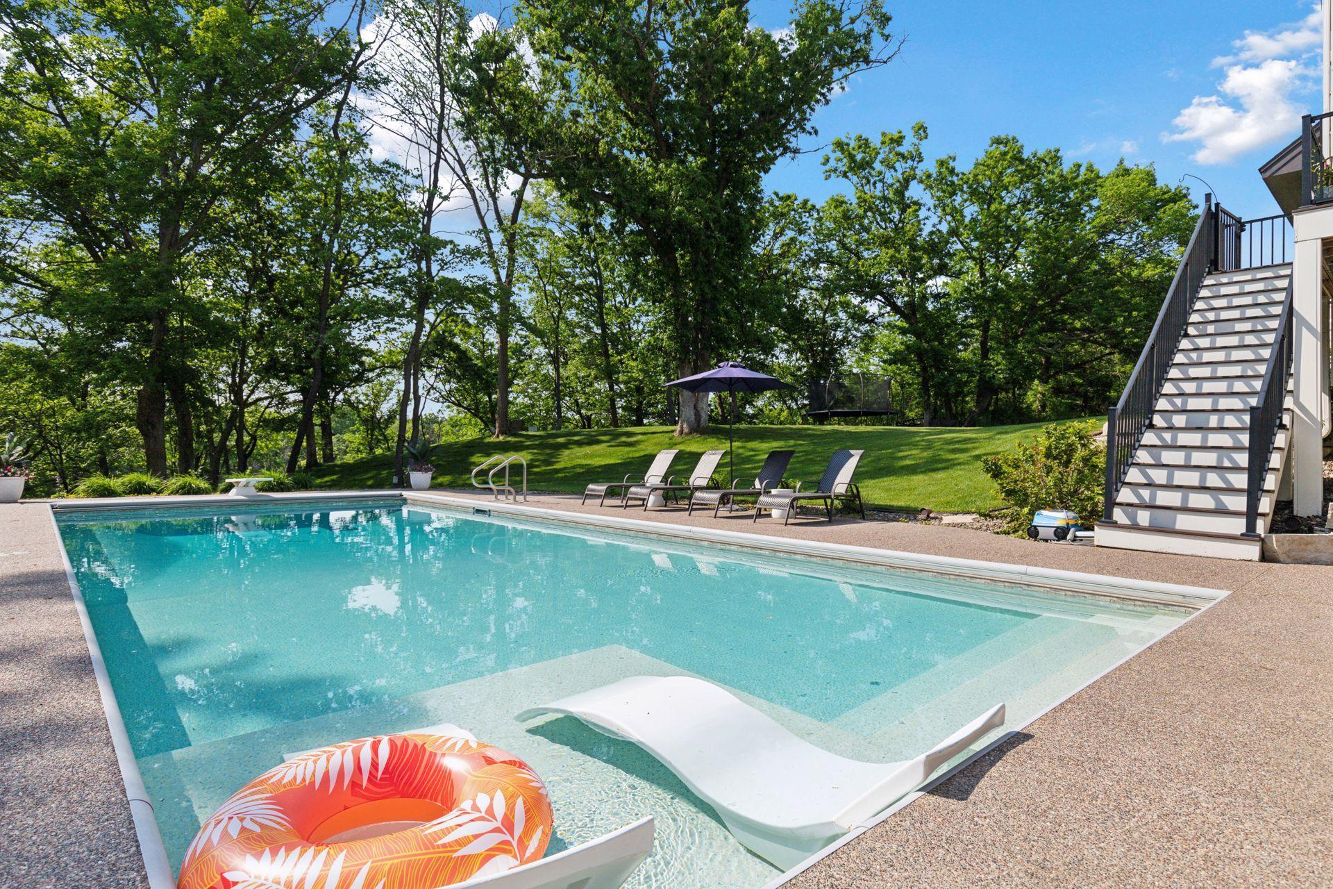 Peaceful poolside setting with partial shade, lush greenery, and clean design. Includes integrated shallow lounging shelf and steps for easy entry—an entertainer’s dream.