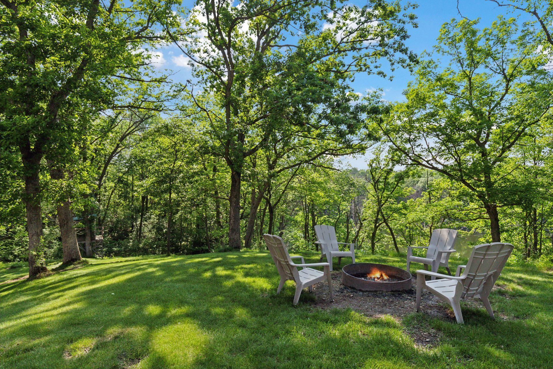 Peaceful firepit seating area surrounded by mature trees—ideal for evening gatherings under the stars or cozy mornings with coffee.