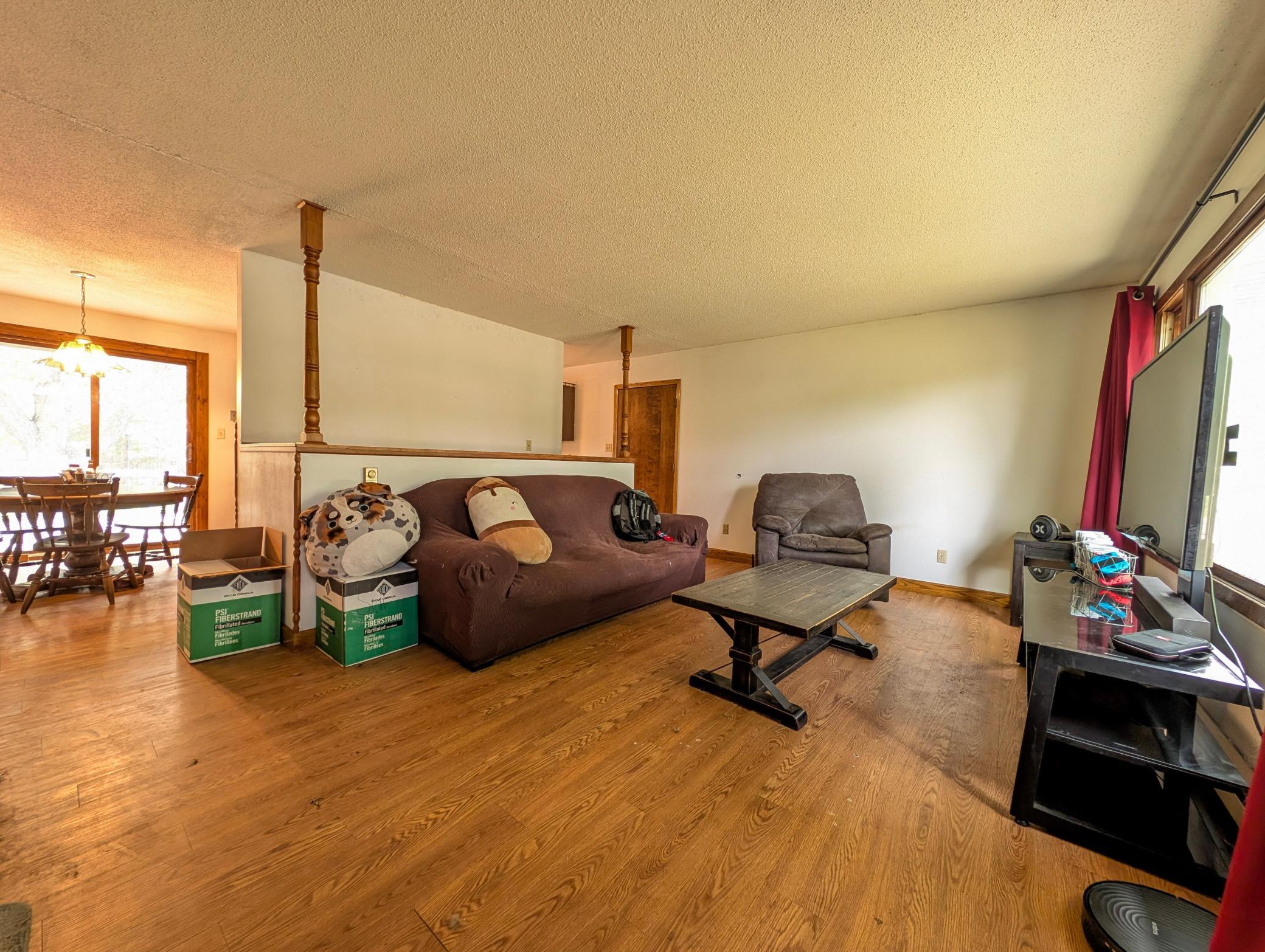 The living room is warm and welcoming, featuring a comfortable space for relaxing or hosting. Large windows bring in great natural light and give the room an airy feel.