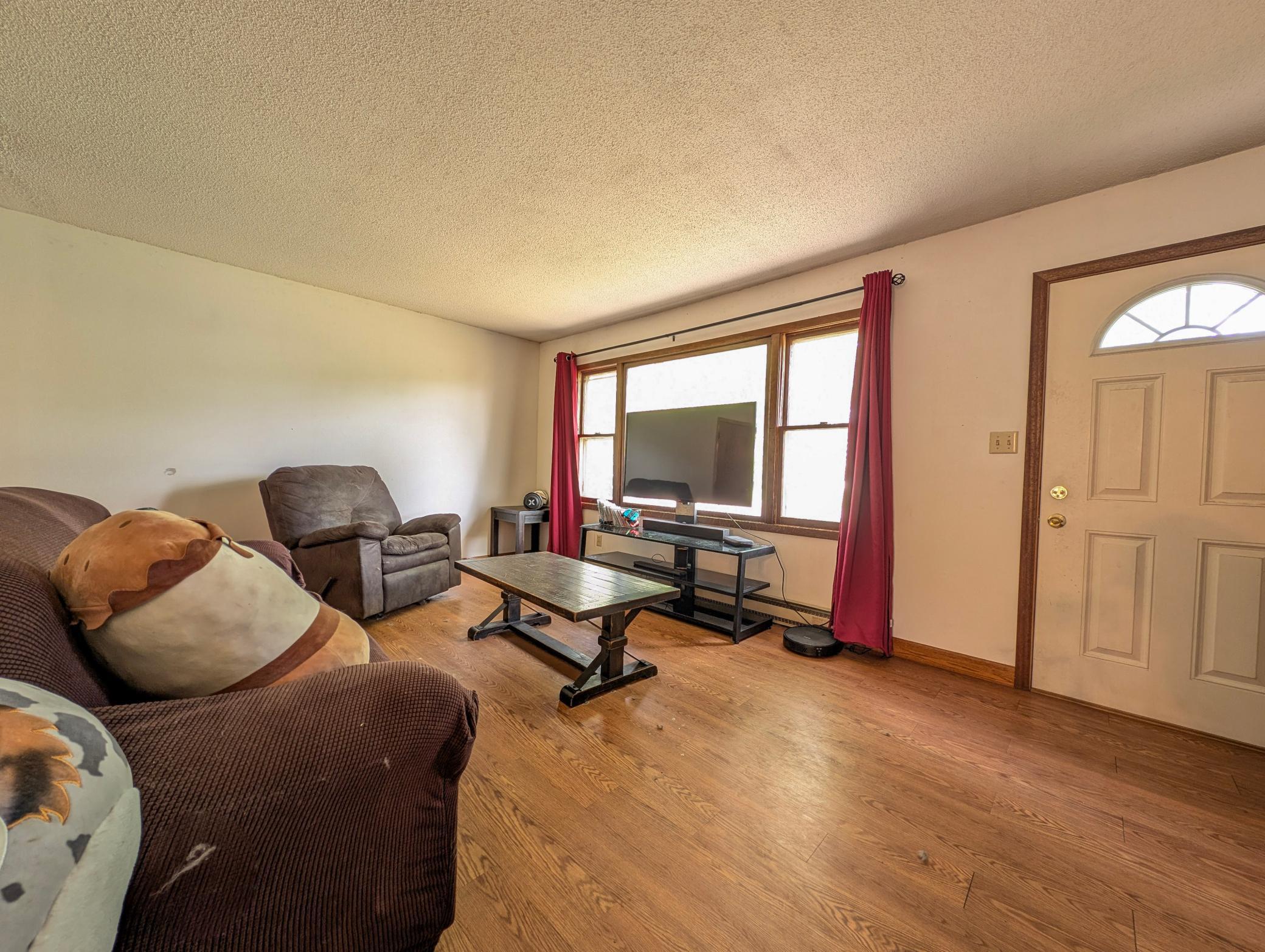 The living room is warm and welcoming, featuring a comfortable space for relaxing or hosting. Large windows bring in great natural light and give the room an airy feel.