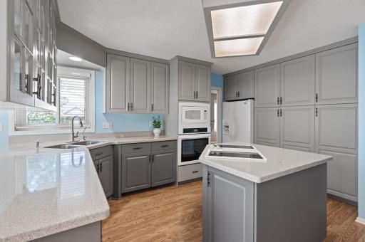 Updated kitchen with quartz countertops, center island, cabinet pull-outs, glass-front doors, and abundant storage.