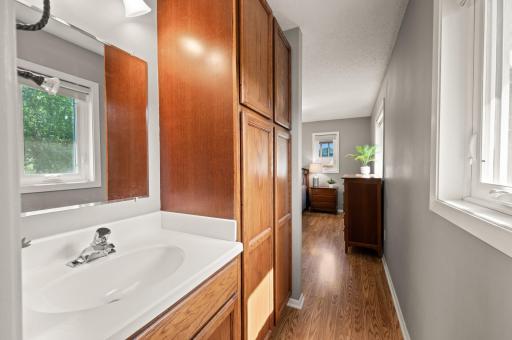 Separate vanity station in the primary bedroom suite with linen and towel storage. Perfect space for a dressing space plus natural light is abundant!
