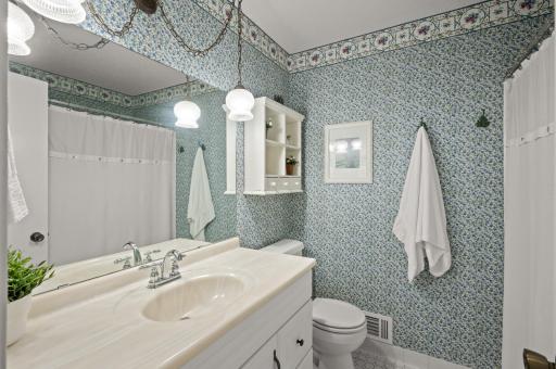 One of two bathrooms upstairs. Coastal vibe with this wallpaper.
