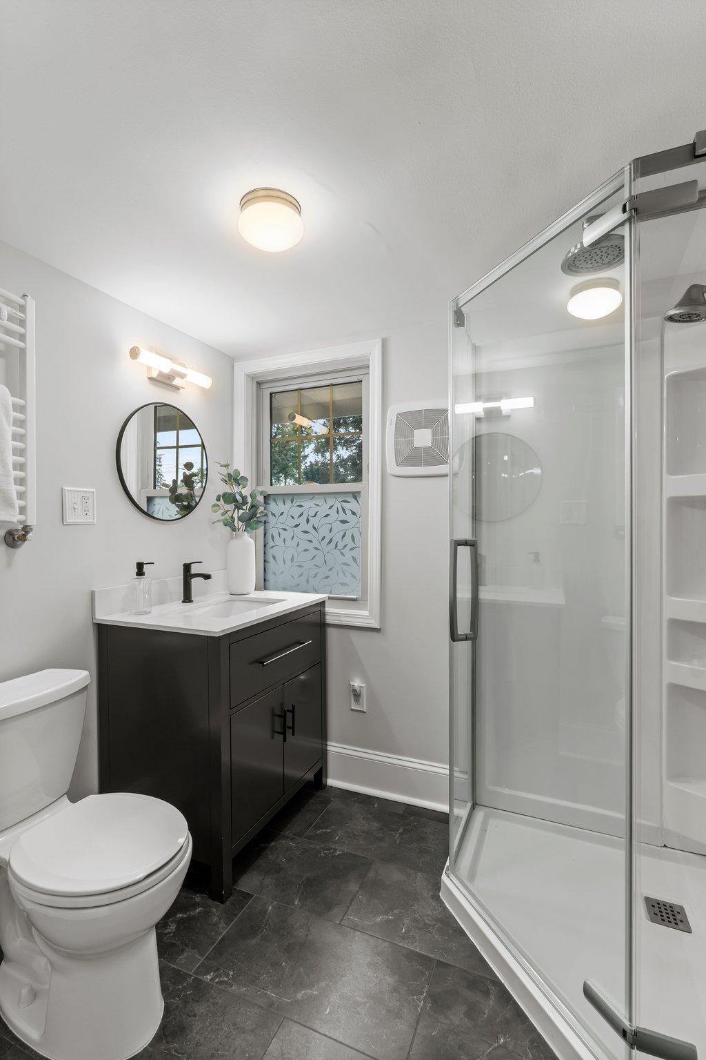 The upper-level ¾ bathroom was completely remodeled in 2024 and includes a walk-in rain shower, heated tile flooring, and modern finishes.