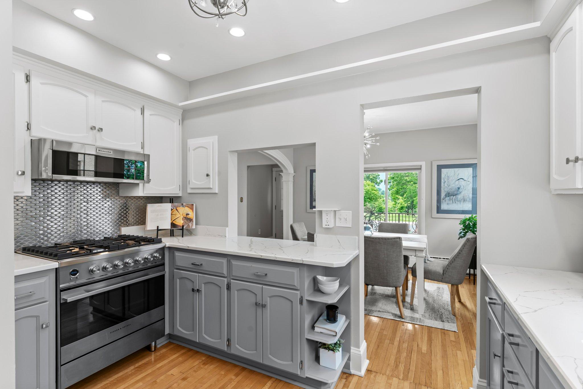 The kitchen, fully remodeled in 2020, features quartz countertops, high-end Fisher & Paykel stainless steel appliances, a tile backsplash, and modern lighting.