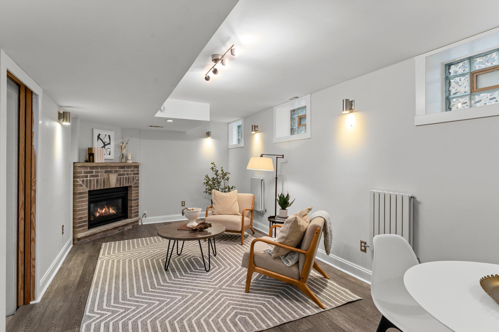 A finished 23x11 family room, completed in 2018, features durable flooring and a gas fireplace with a brick surround—an inviting space for movie nights or relaxing with guests.
