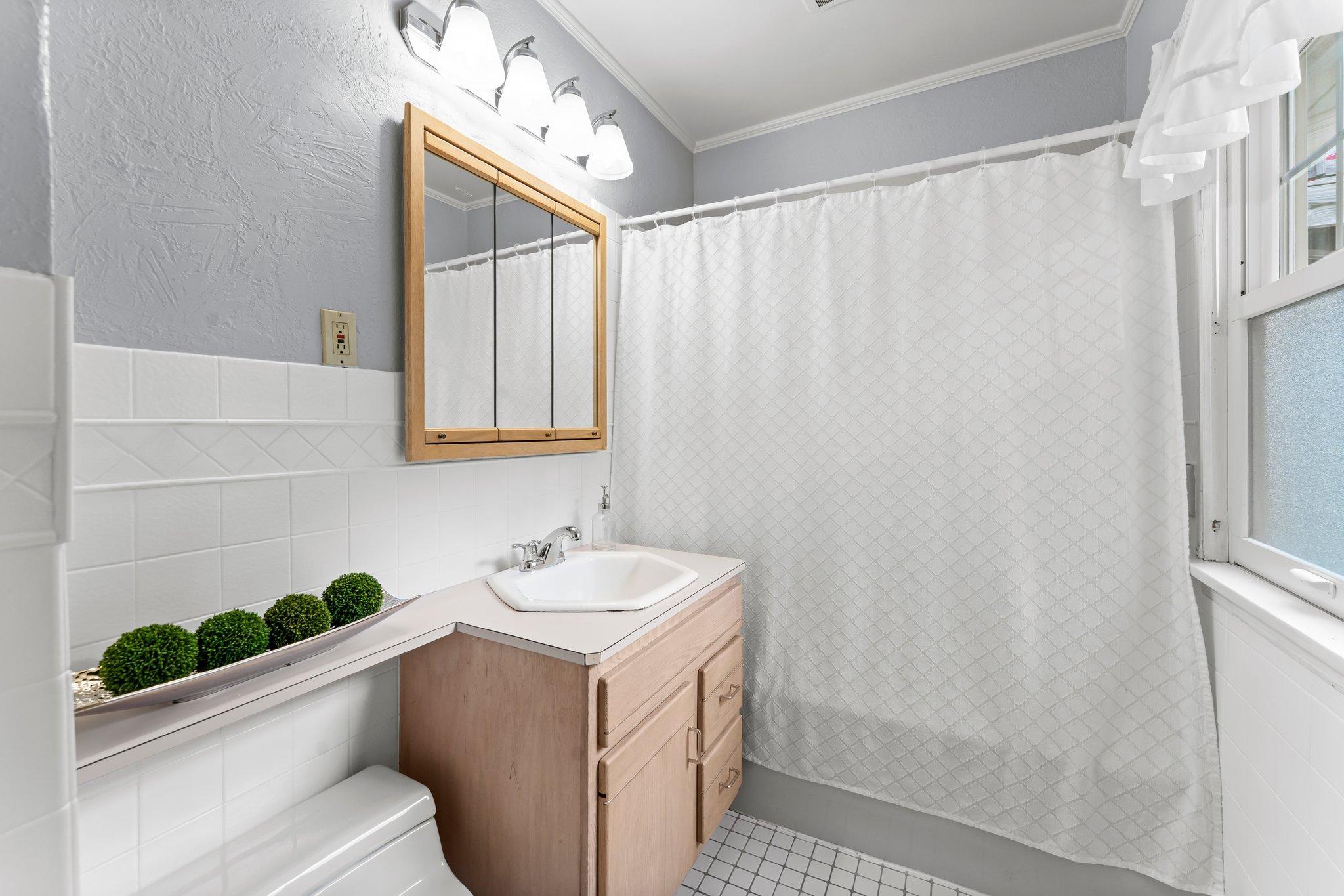Nearby is a full bathroom with tiled floors, a tub/shower combo with tile surround, and a convenient hallway closet for extra storage.