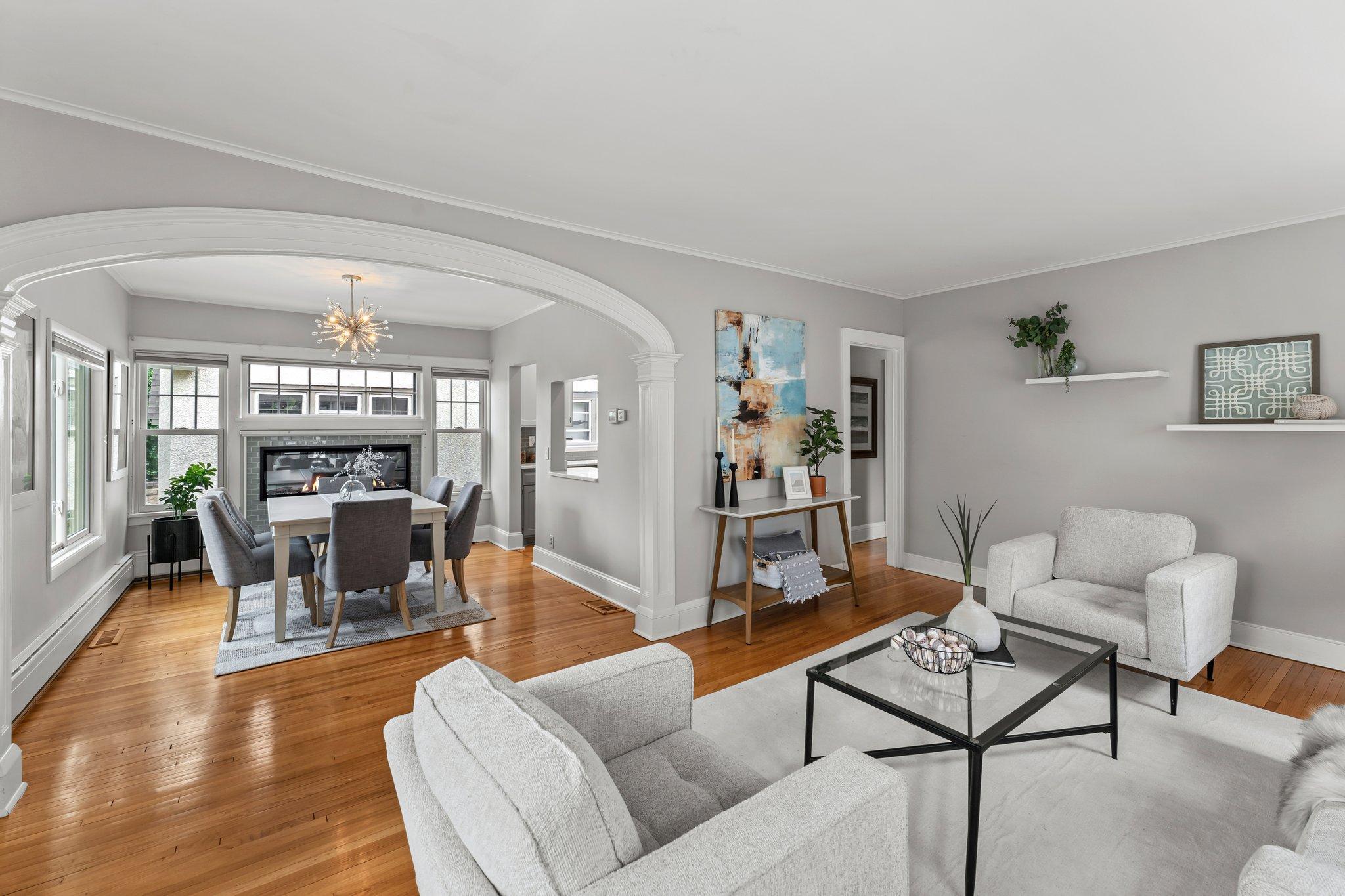 Step inside to a sunlit living room with rich wood flooring, elegant crown molding, and a detailed arched doorway that adds timeless character.