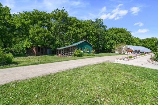Reverse view of tool shed, privy, wood storage, and greenhouse in background.