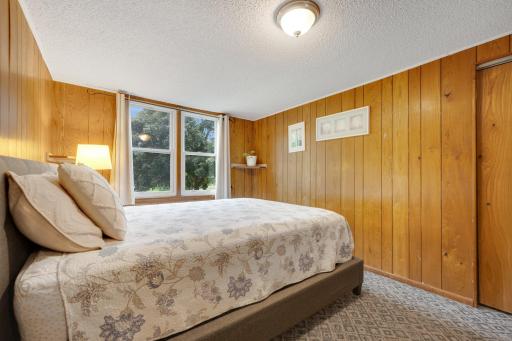 Warm wood paneling make this bedroom a true cozy retreat. Behind the door in the right of this picture is a large walk in closet!