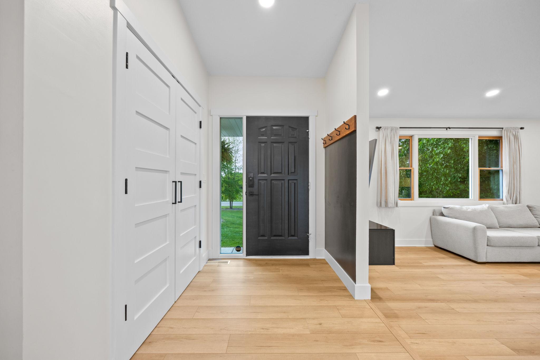 Foyer with coat hooks and front closet with storage organization system.
