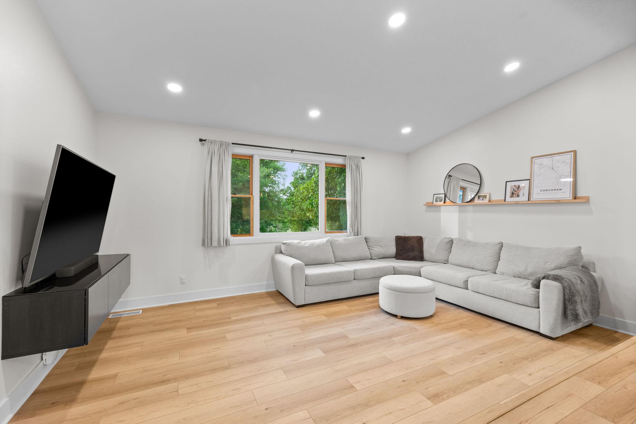 Spacious main level sunken living room with recessed lighting, modern floating cabinetry, & LVP flooring.