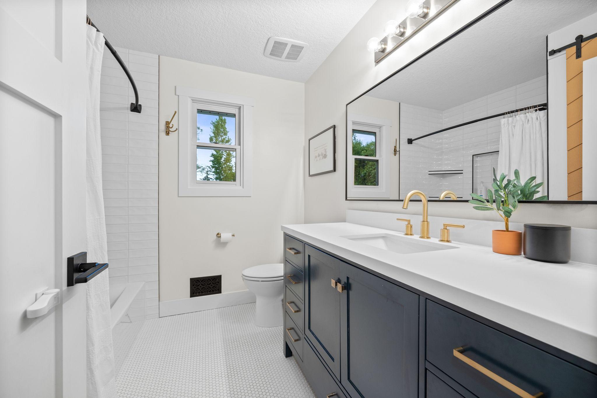 Main level full bathroom with tiled floors and shower, and soft close vanity.