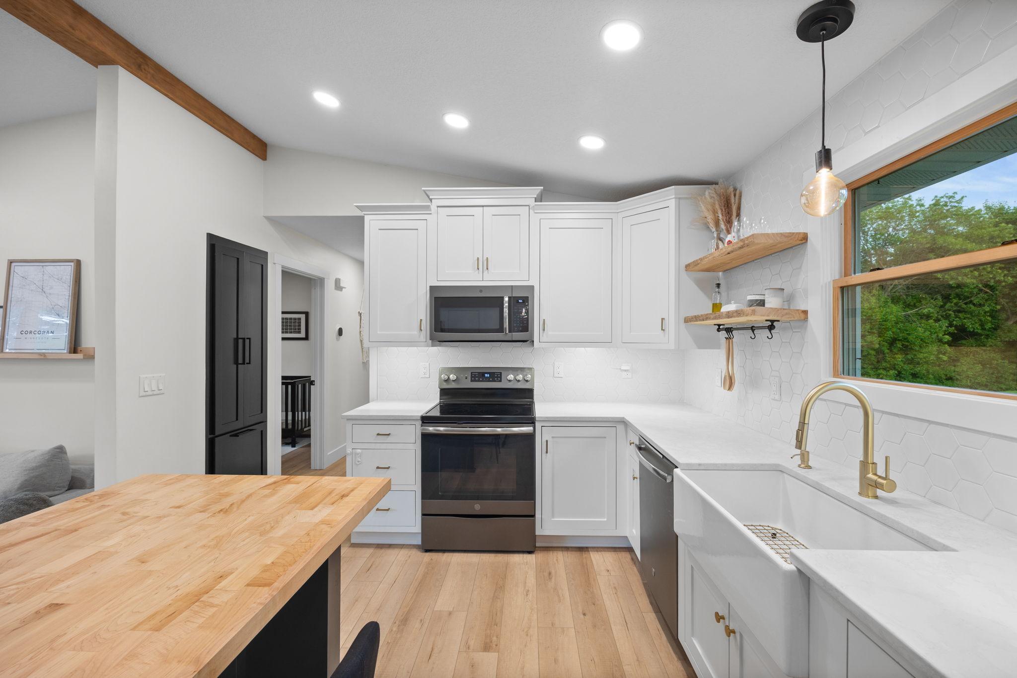 GE Slate appliances, farmhouse sink, hexagon tile backsplash, floating shelves, custom pantry with toe-kick garbage storage.