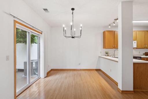 Dining area with hardwood floors and sliding glass doors to exterior patio. Updated farmhouse style lighting.