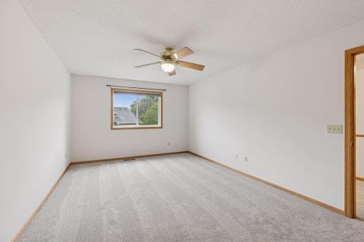 Bedroom with ceiling fan and brand new carpet and paint.