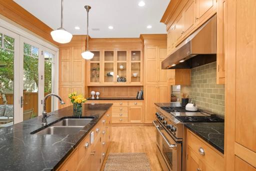 The meticulously renovated kitchen is award-winning and outfitted with custom cabinetry (with inset doors), high-end appliances, stone counters, tile backsplash, quality fixtures, planning desk, and a generous center island.