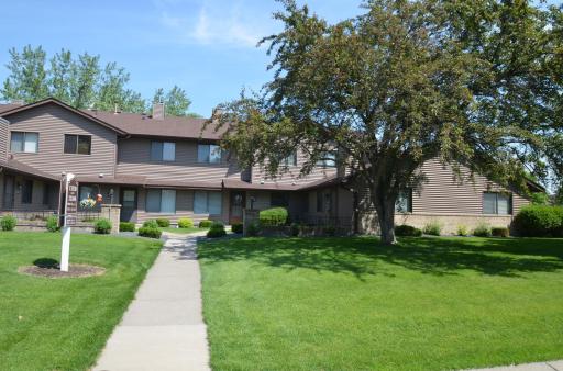 Spacious front lawn with manicured landscaping and a walkway leading to the front entrance of this charming townhome.