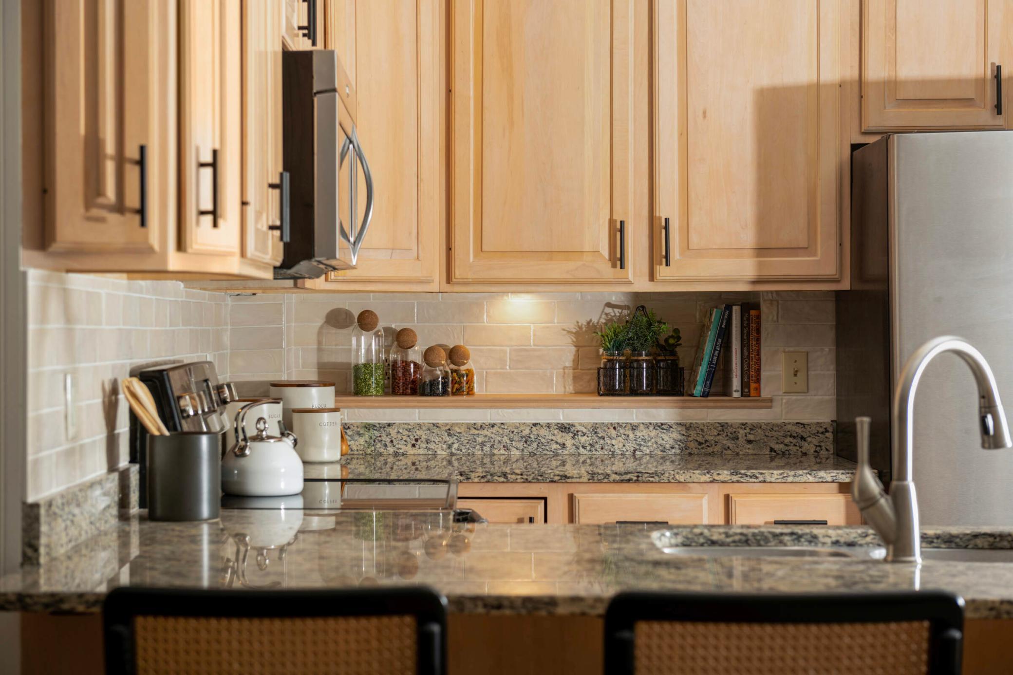 Scandinavian style wood cabinets combine beautifully with the new artisan Spanish tile, backsplash and the warm tones of the granite countertops.