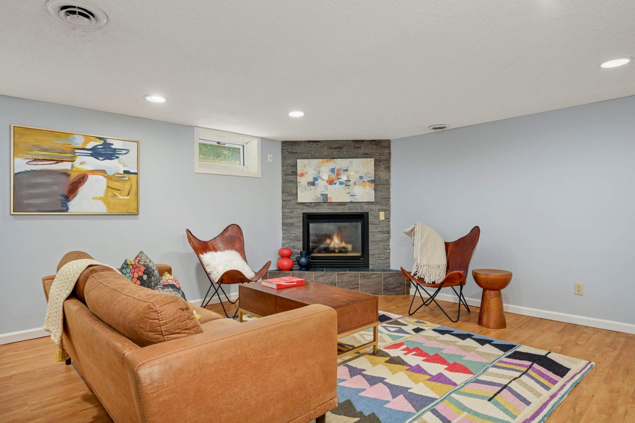 Cozy lower-level family room featuring a stone gas fireplace, recessed lighting, and plenty of space for relaxing or entertaining.